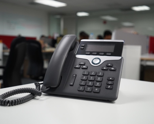 A black phone system on a white desk
