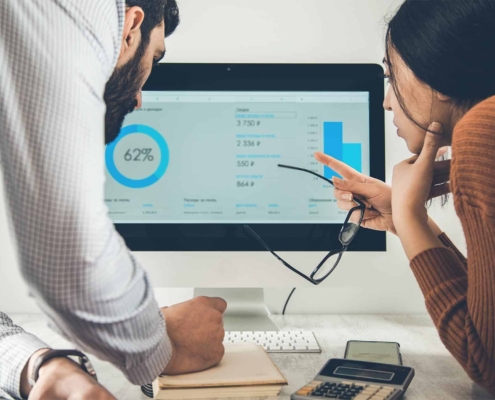 Two business people looking at charts on computer