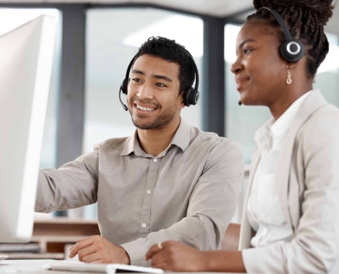 Two people with headsets collaborating at computer